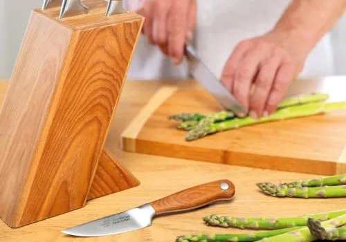 uomo che taglia asparaci con un coltello dal manico di legno